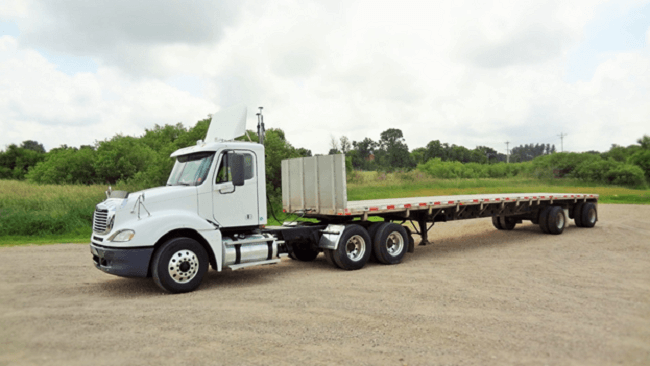 Flatbed trailer coupled to a day-cab tractor ready for open-deck freight