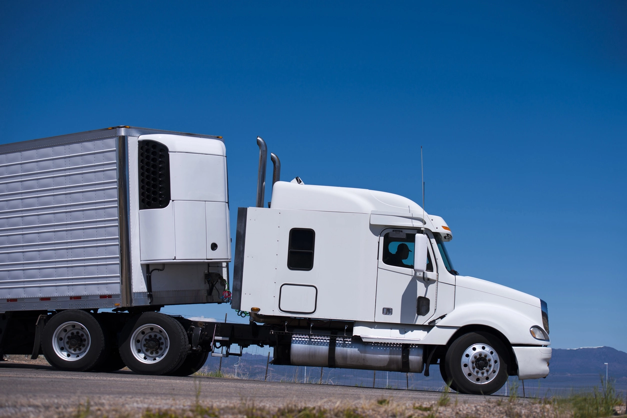 White refrigerated reefer trailer running under a clear blue sky